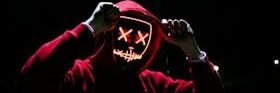 A spooky illuminated mask figure with a red hoodie in a dark setting, perfect for Halloween themes.